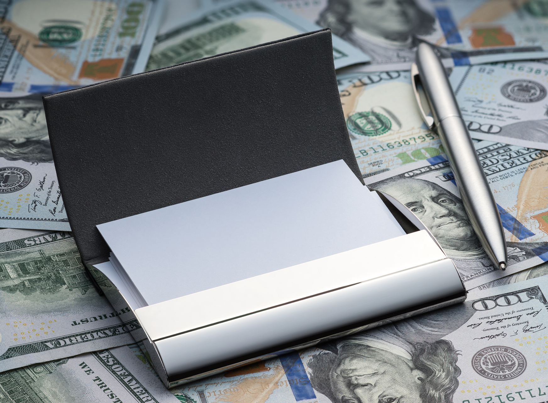 Business card holder and pen on dollars background
